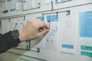 Infografica colorata e dettagliata che illustra i passaggi chiave per diventare un designer UX/UI. I punti includono l'apprendimento dei principi fondamentali del design UX/UI, lo sviluppo di un senso estetico attraverso l'analisi critica di siti web e app, l'investimento in software di design professionale come Figma, Sketch e Adobe XD, la creazione di un portfolio di lavori che dimostri competenze e creatività, la ricerca di feedback costruttivo per il miglioramento continuo e l'acquisizione di esperienza lavorativa pratica. Ogni passaggio è rappresentato da icone suggestive e collegato da una linea curva per guidare visivamente l'utente attraverso il percorso di carriera, sottolineando l'importanza dell'iterazione e dell'apprendimento continuo nel campo del design UX/UI.